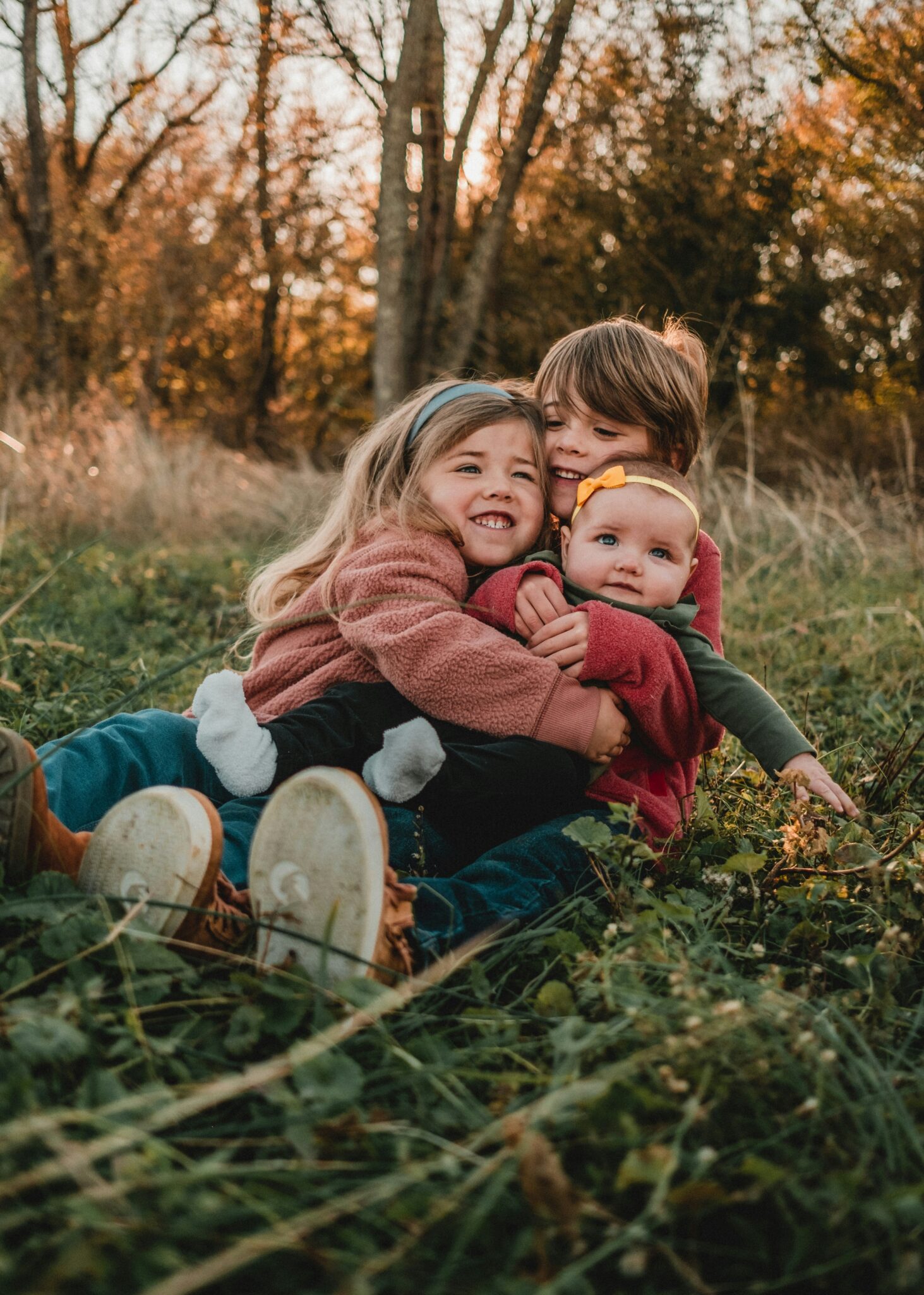 Mom and kids snuggled in the grass in warm fall colors