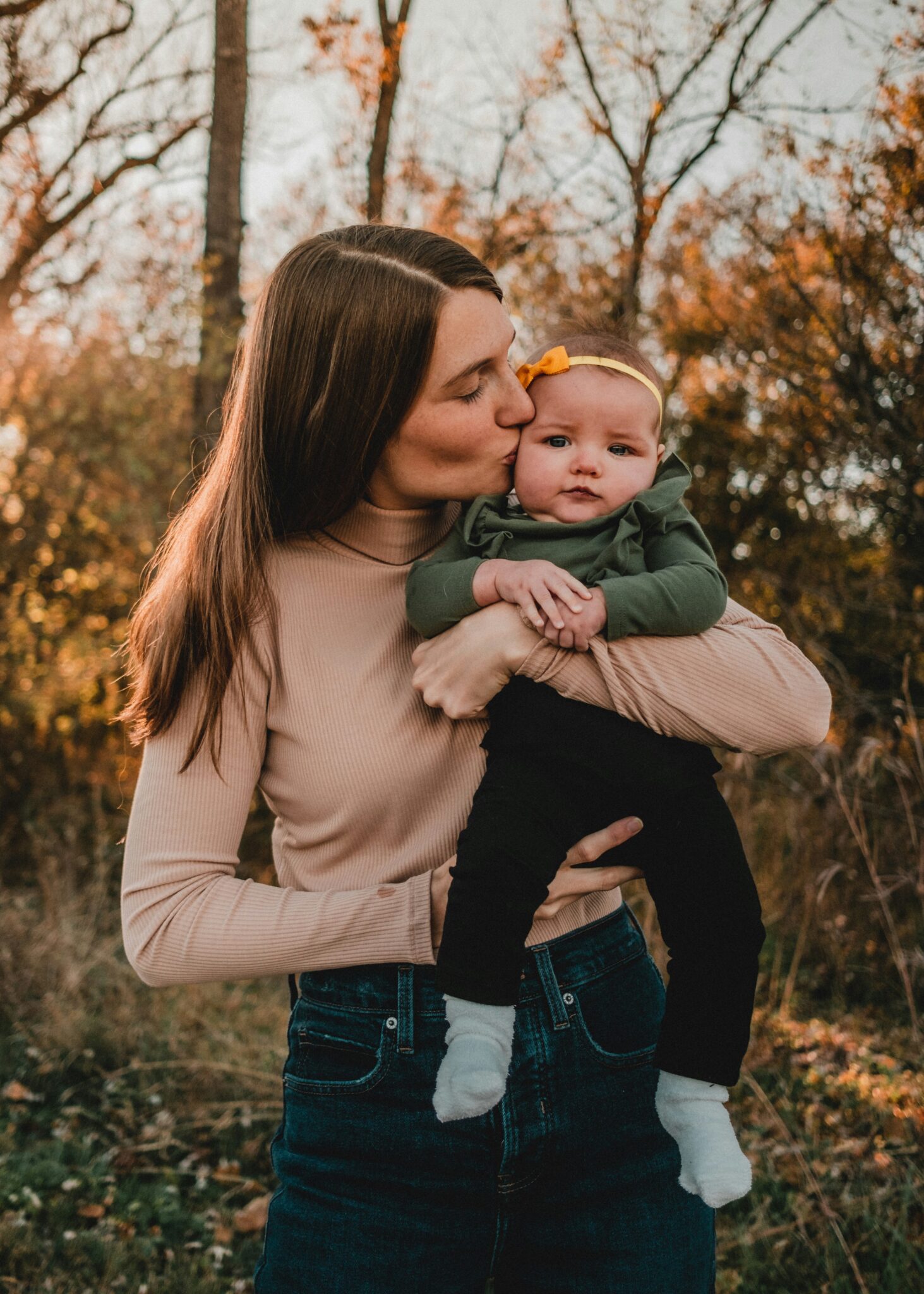 Family sitting in autumn leaves wearing warm tones
