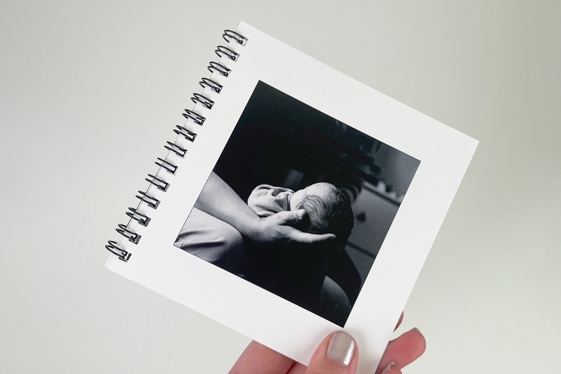 Wire bound photo book with a black and white photo of a baby's hand