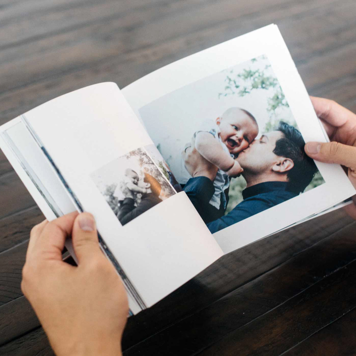 Dad kissing his baby in an open soft cover photo book